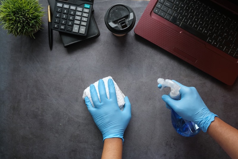 tägliche putzroutine home office tisch wischen mit putzmittel und lappen