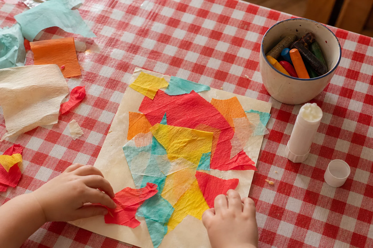 Basteln mit Kleinkindern: bunte Reißcollage auf dem Küchentisch