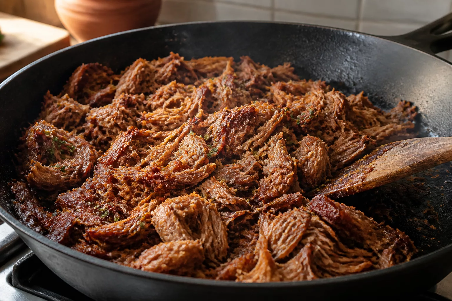 Zerzupftes Schweinefleisch wird in der Pfanne knusprig angebraten