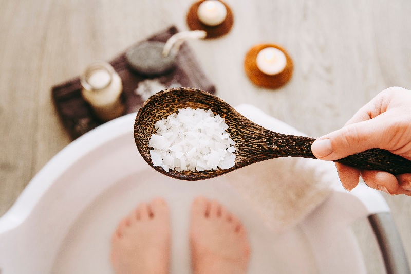 adding magnesium chloride vitamin salt in foot bath water, solution. magnesium grains in foot bath water are ideal for replenishing the body with this essential mineral, promoting overall wellbeing.