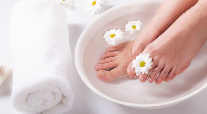 female,feet,with,spa,bowl,,towel,and,flowers,on,white