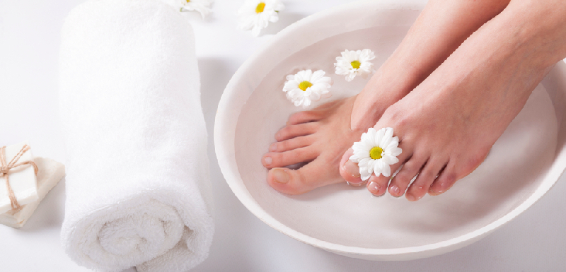 female,feet,with,spa,bowl,,towel,and,flowers,on,white