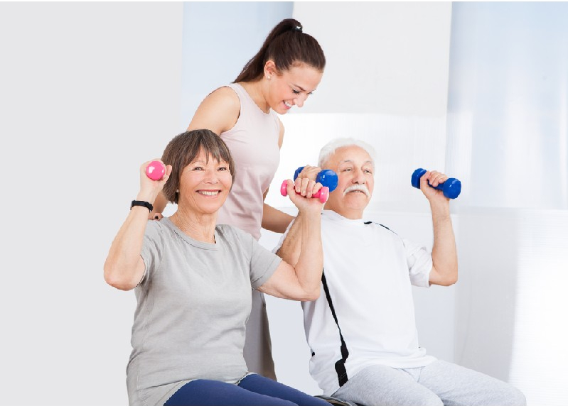 trainer assisting senior couple with dumbbells