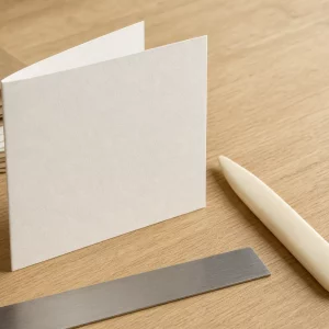 Karten selber basteln: aufgeklappte Klappkarte mit Falzbein auf Holztisch