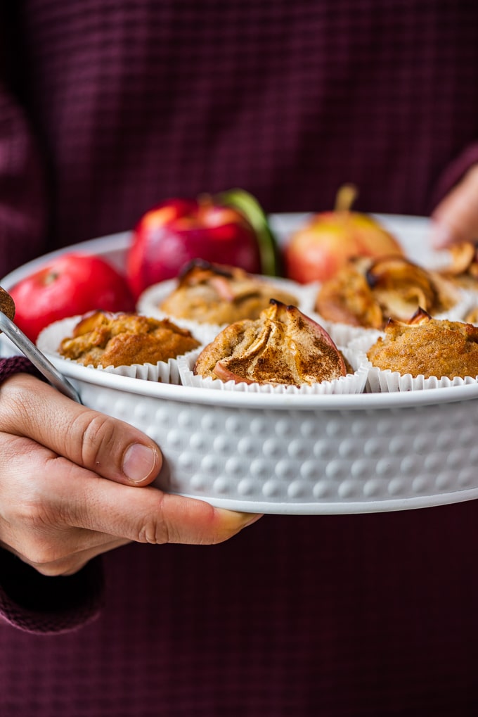 muffins vegan apfel zimt muffins mit streusel frau hält teller mit apfel zimt muffins