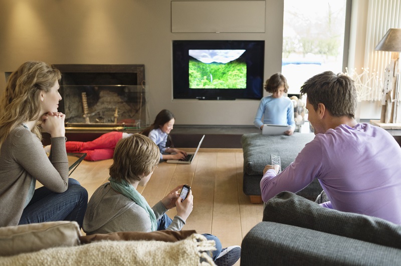 family using electronic gadgets in a living room