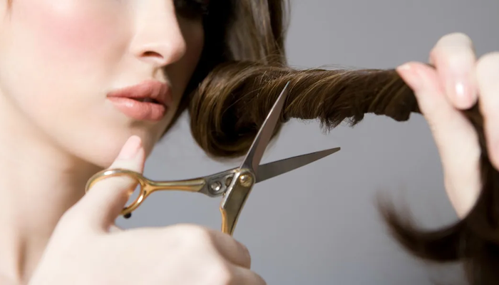 die haare oefter schneiden lassen eine frau mit braunen haare schneidet ihre haare (1)