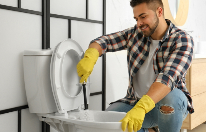young,man,cleaning,toilet,bowl,in,bathroom