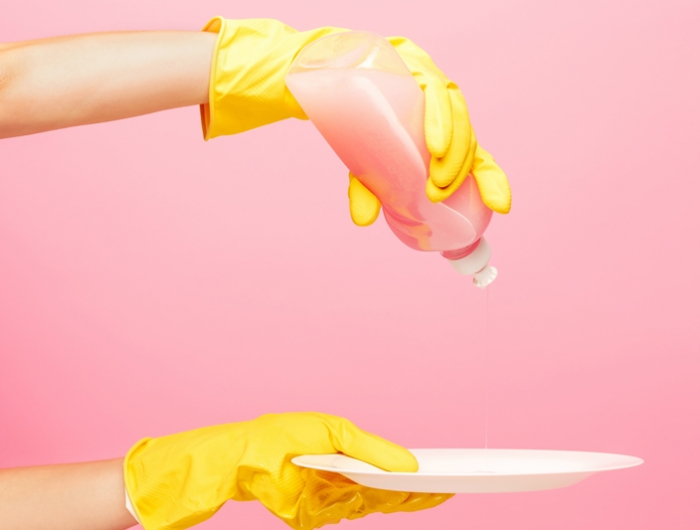hands in yellow protective gloves washing a plate
