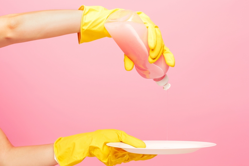 hands in yellow protective gloves washing a plate