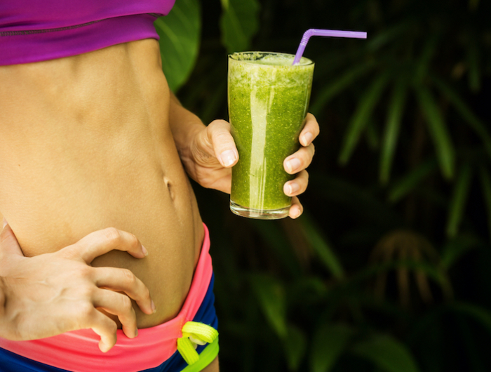 athletic girl holding a green smoothie