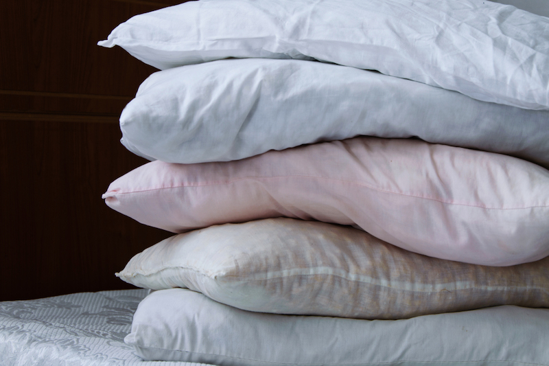 close up of stacked pillows on bed at home