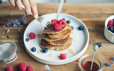 frau isst pancakes mit himbeeren und heidelbeeren