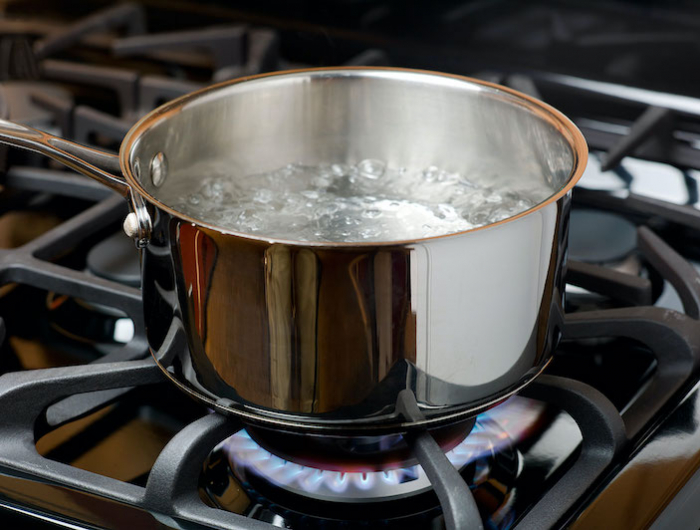 water bubbles and boils on a gas stove or range in a home kitchen. blue flame and stainless steel pot. credit: ryersonclark/getty
