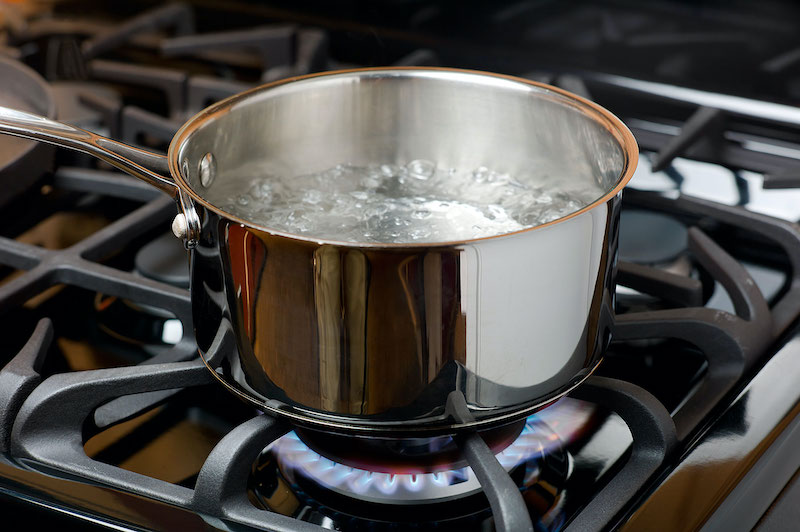 water bubbles and boils on a gas stove or range in a home kitchen. blue flame and stainless steel pot. credit: ryersonclark/getty