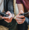 cropped image of young men playing video games while sitting on sofa at home