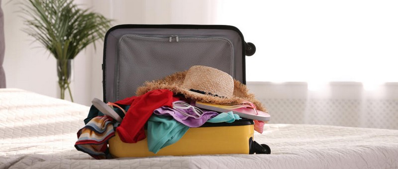 modern suitcase full of clothes on bed indoors. space for text