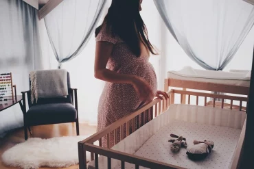 babybett waehlen schwangere frau vor einem bettchen