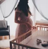 babybett waehlen schwangere frau vor einem bettchen