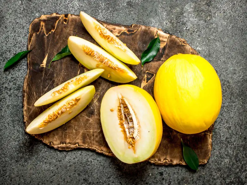 melonen desserts fruehstueck frische gelbe honigmelone schneiden auf schneidebrett