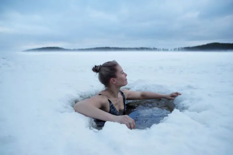 sisu finnland leben eisbad geniessen frau schwimmt im gefrorenem see 