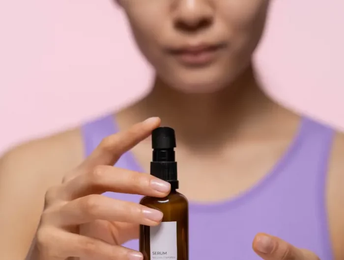 was bedeutet nachhaltige kosmetik nachhaltige produkte asiatische frau mit lila top haelt braune flasche fuer kosmetik
