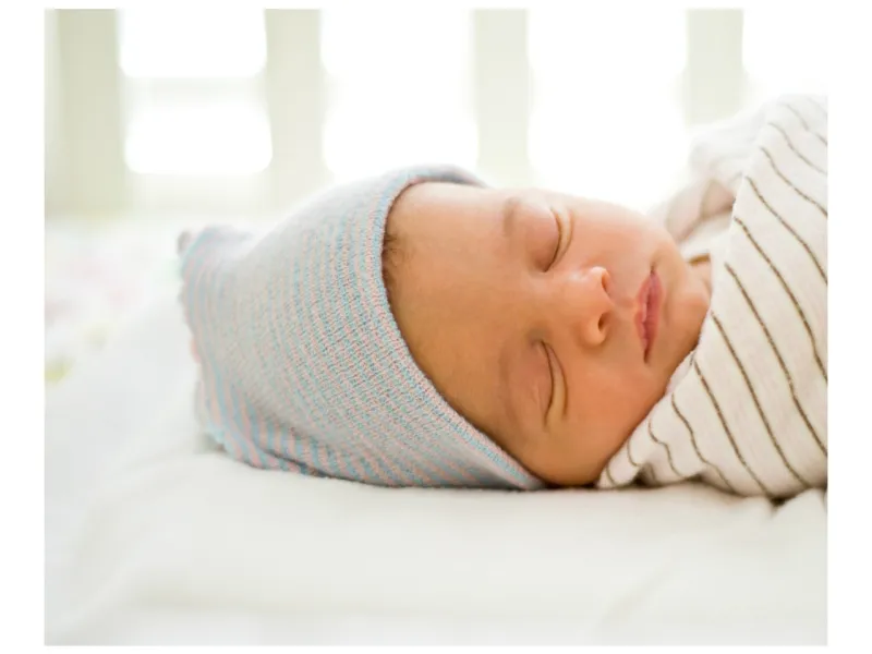 kleines baby schläft weiße mütze bettwäsche gestreift