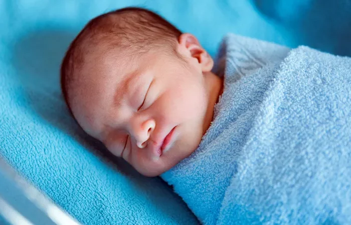 neugeborens baby schläft umwickelt blaue bettwäsche