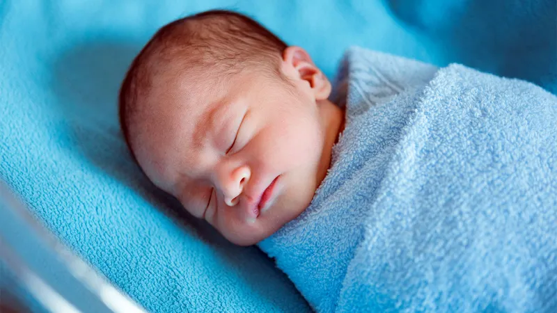 neugeborens baby schläft umwickelt blaue bettwäsche