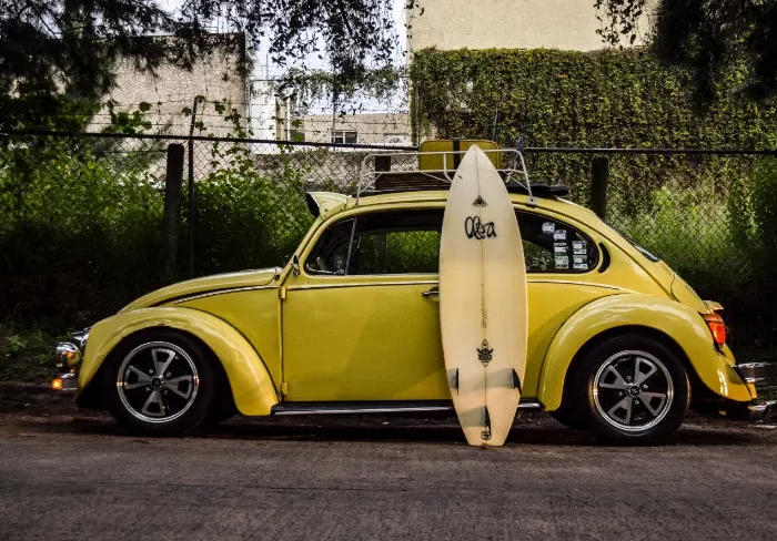 retro gelbes auto mit einem angelehnten surfbrett