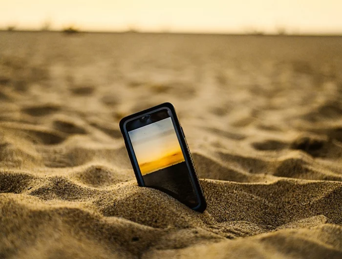 smartphone case reinigen ein handy im sand am strand