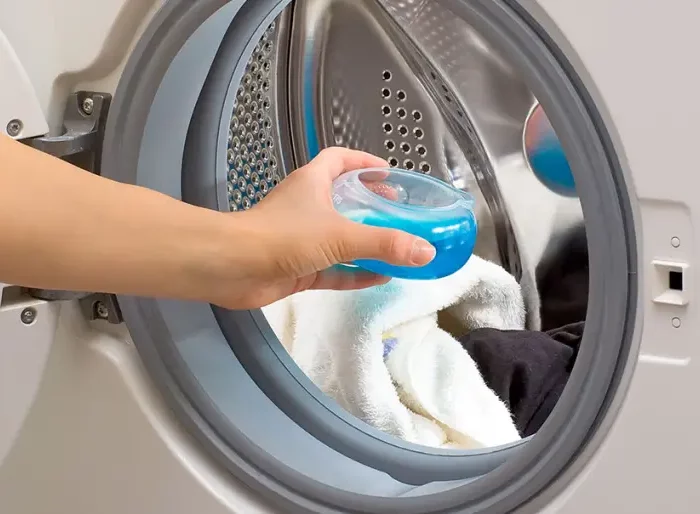 wie dosiert man waschmittel richtig zu viel waschmittel dosierer mit blauem waschmittel in trommel stellen
