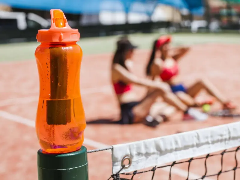 wie werden wasserflaschen gereinigt trinkflasche mit clor reinigen orange trinkflasche aus kunststoff auf tennisplatz