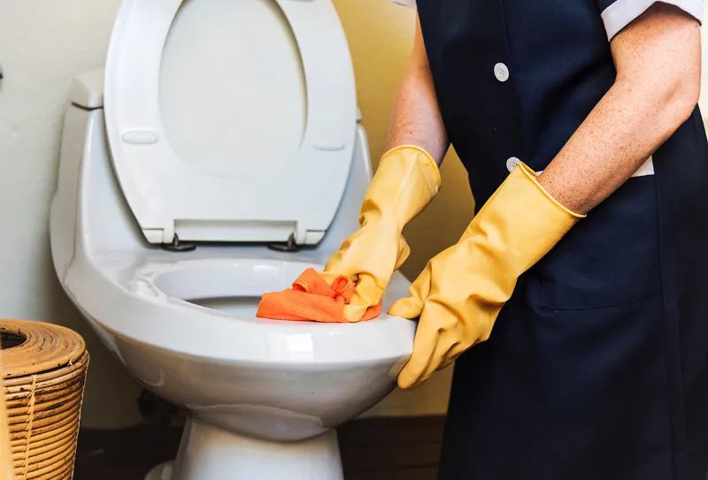 person mit gelben gummihandschuhen reinigt eine toilette