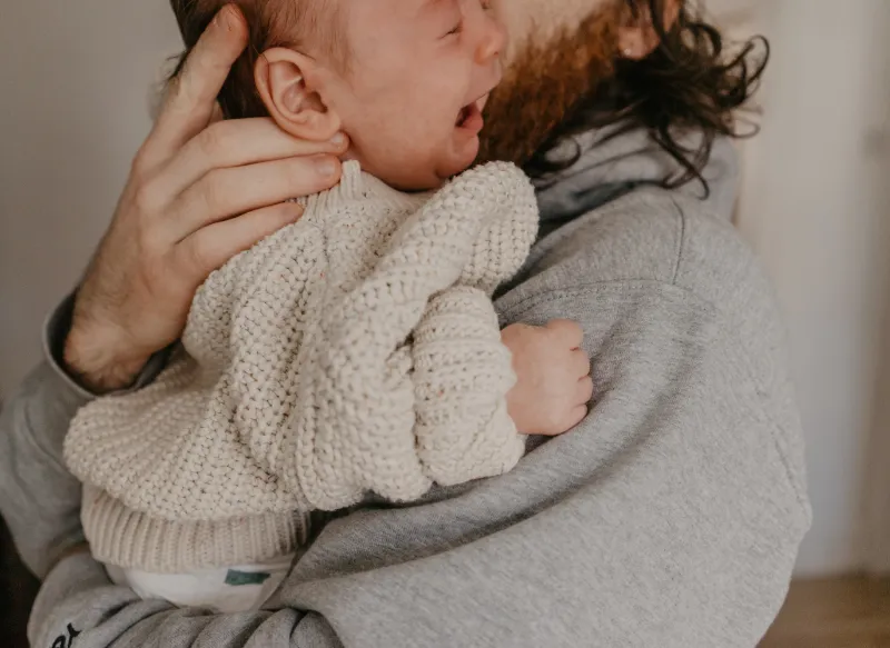 vater umarmt und beruhigt sein schreiendes baby