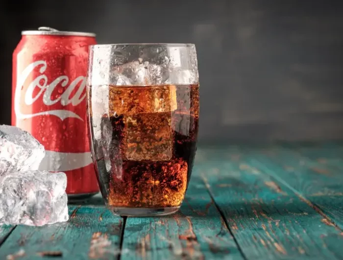 angelaufenes edelstahl reinigen coca cola glas mit kaltem getraenk dose cola im hintergrund