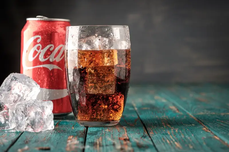 angelaufenes edelstahl reinigen coca cola glas mit kaltem getraenk dose cola im hintergrund