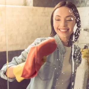 frau reinigt ihre stark verkalkte duschtuer mit hausmitteln