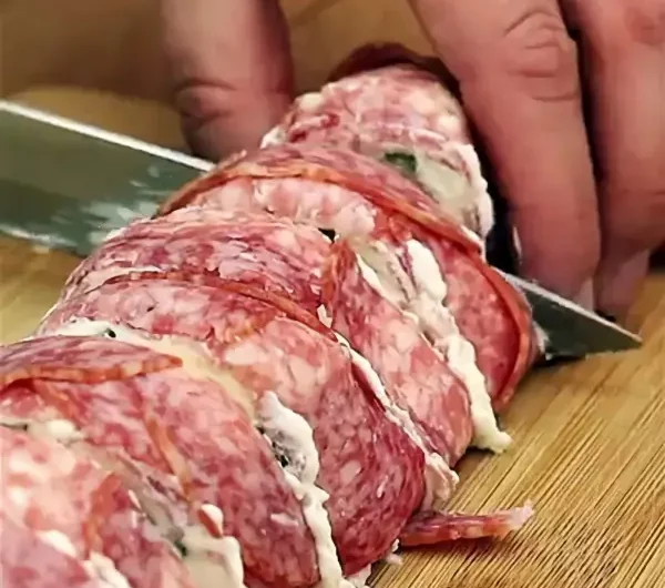 einfaches fingerfood fuer silvester roellchen aus salami mit kaese mann schneidet roellchen