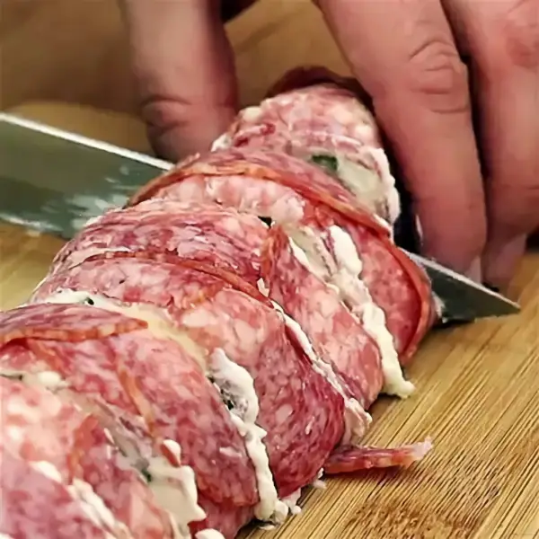 einfaches fingerfood fuer silvester roellchen aus salami mit kaese mann schneidet roellchen