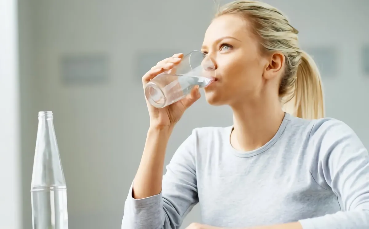 blonde frau trinkt wasser aus einer flasche