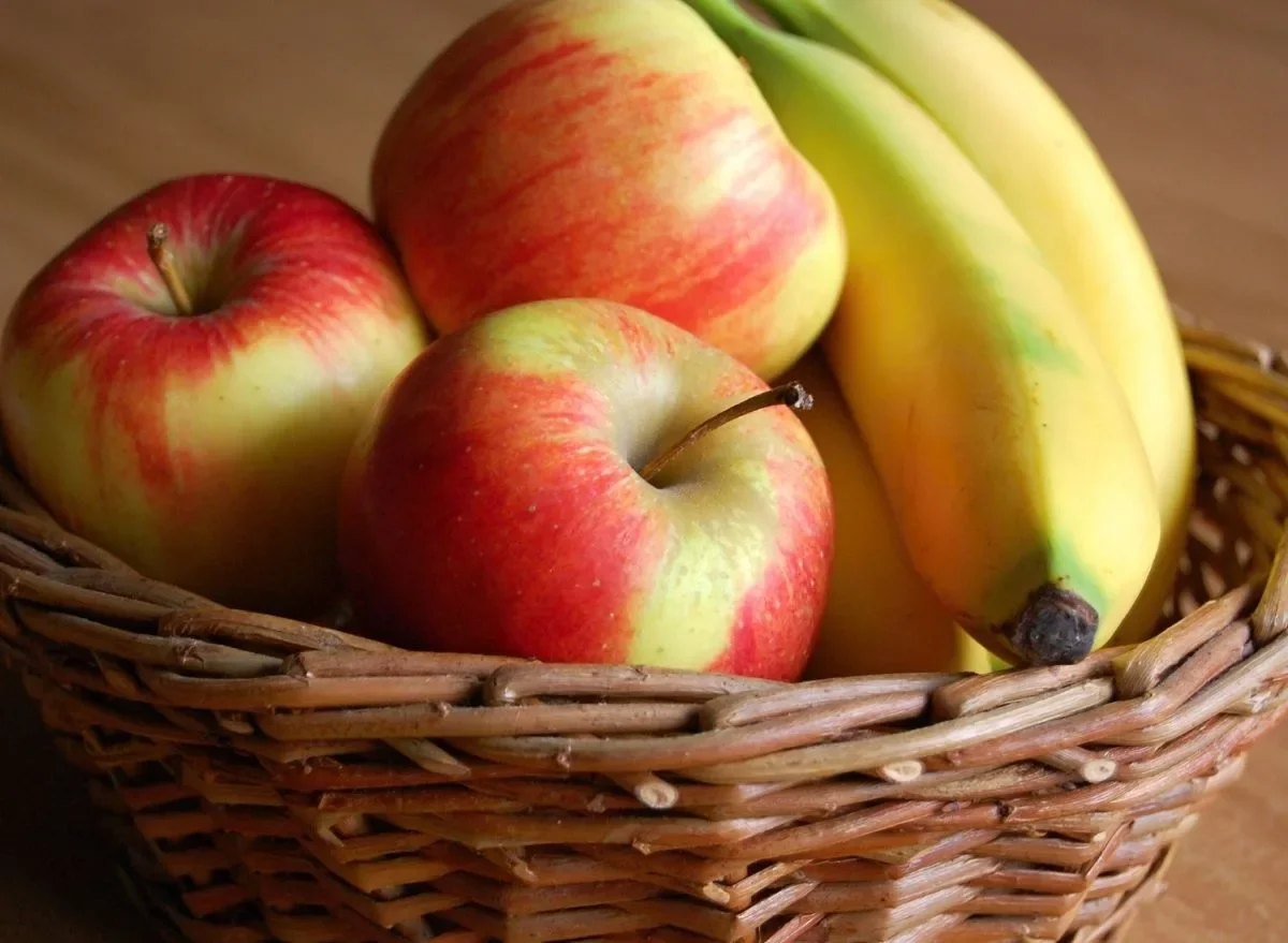 rote aepfel und gelbe bananen zusammen in einem korb lagern