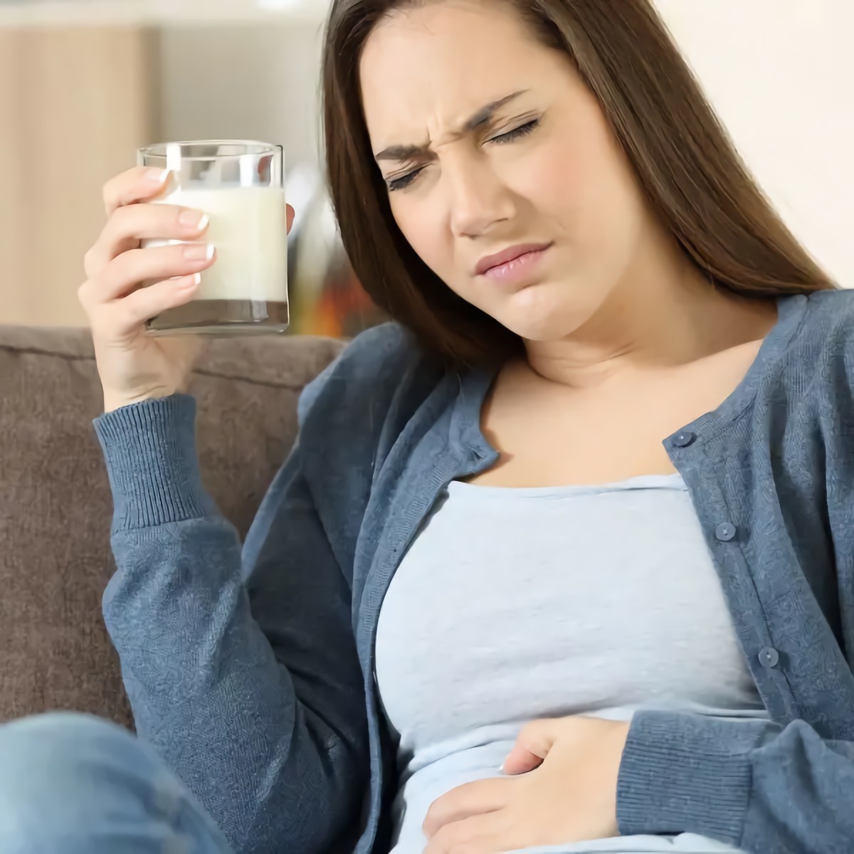 wie kann man merken dass man laktoseintoleranz hat laktoseintoleranz mit alter junge frau am sofa haelt glas milch leidet an bauchschmerzen