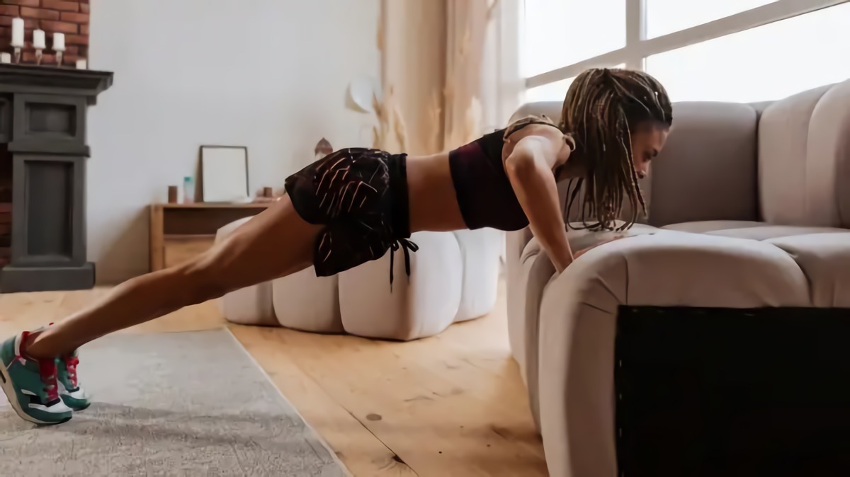 wie oft sollte man ein home workout machen sport im alltag integrieren junge frau macht push ups am sofa