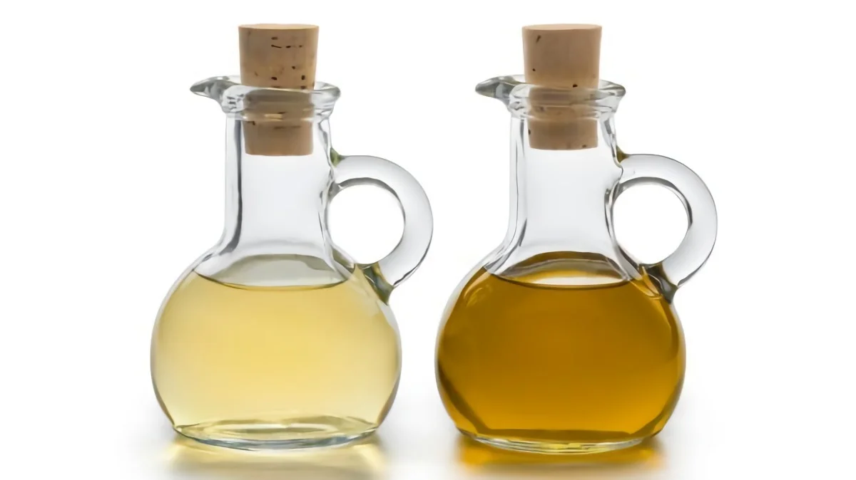 zwei glasflaschen mit korkverschluss, gefuellt mit olivenoel und apfelessig