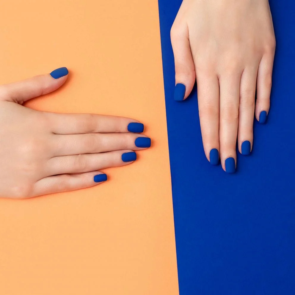 frau mit blauem gelnagellack auf orangem und blauem hintergrund