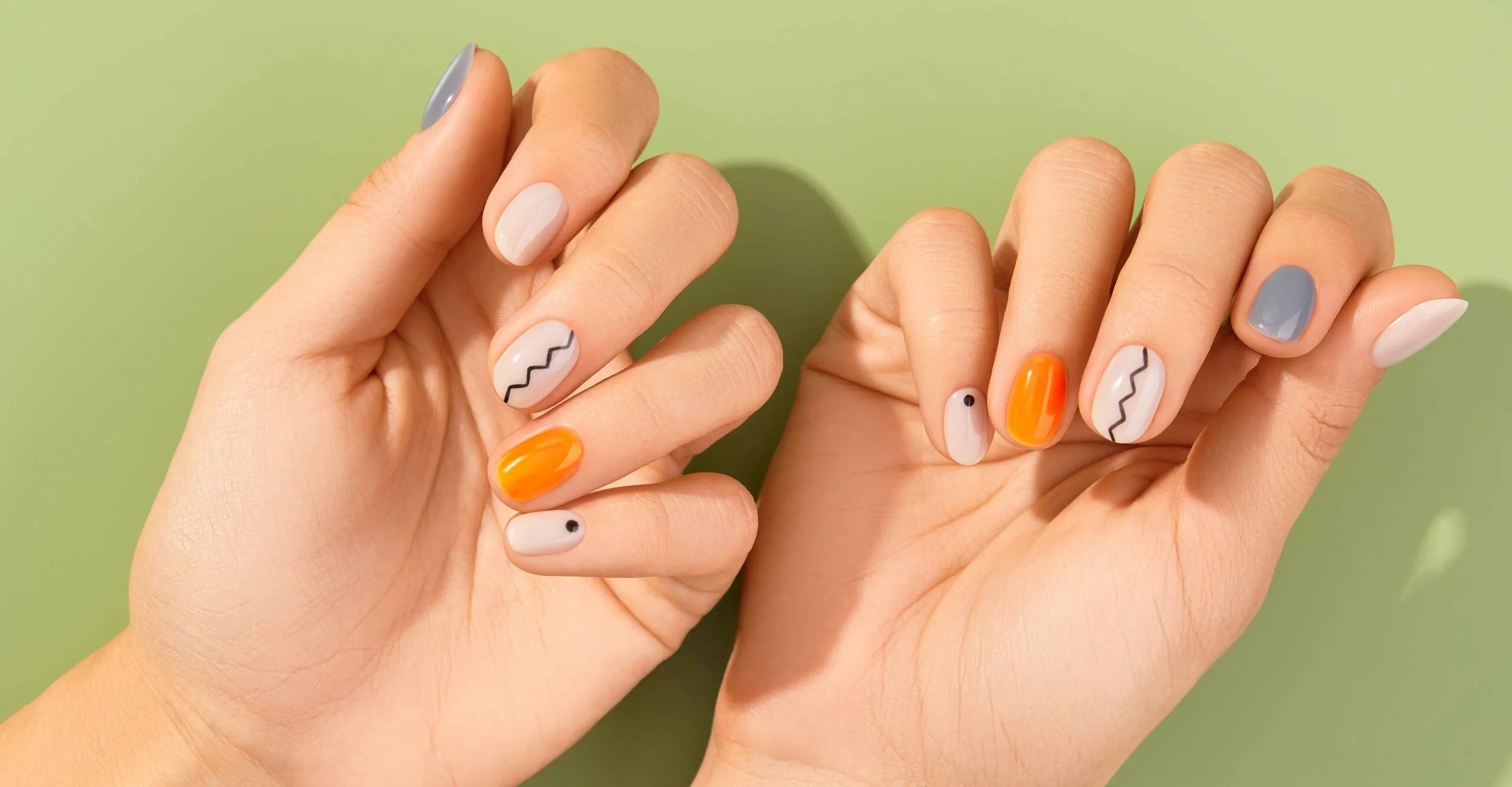 frauen haende mit bunten gel nagellack mit orange lila und weißen farben