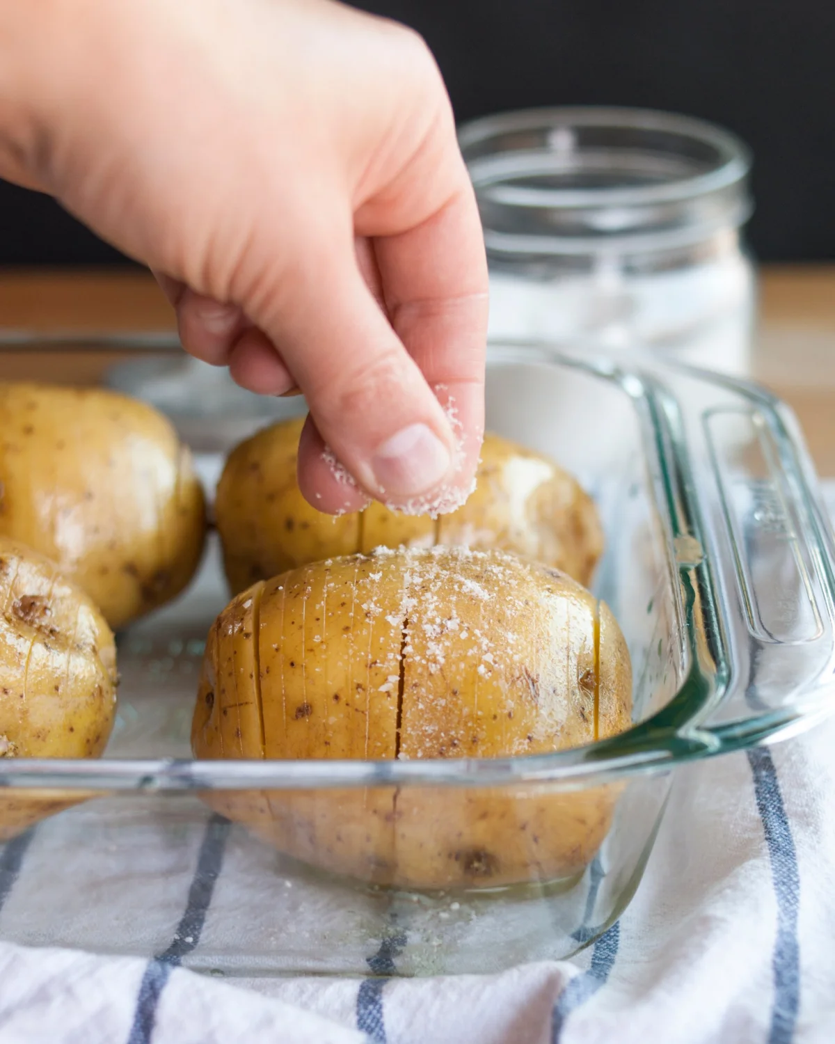 kartoffeln in der glasschale vor dem backen mit meersalz bestreuen