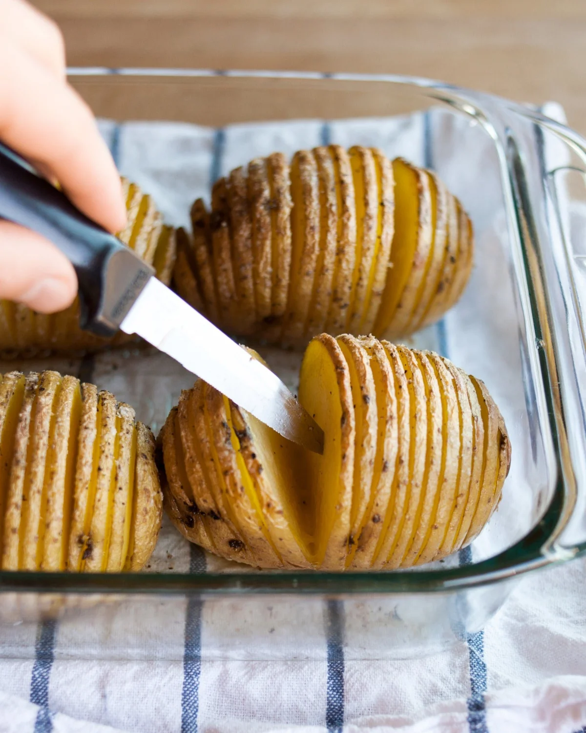 kochen von hasselback kartoffeln und pruefen mit einem messer ob sie fertig sind