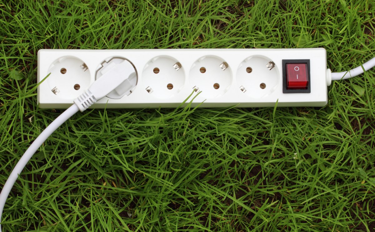 electric,power,receptacle,and,plug,on,the,grass,,energy,concept